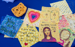 A blue background with a group of yellow and blue quilt squares with drawings and inspirational messages.
